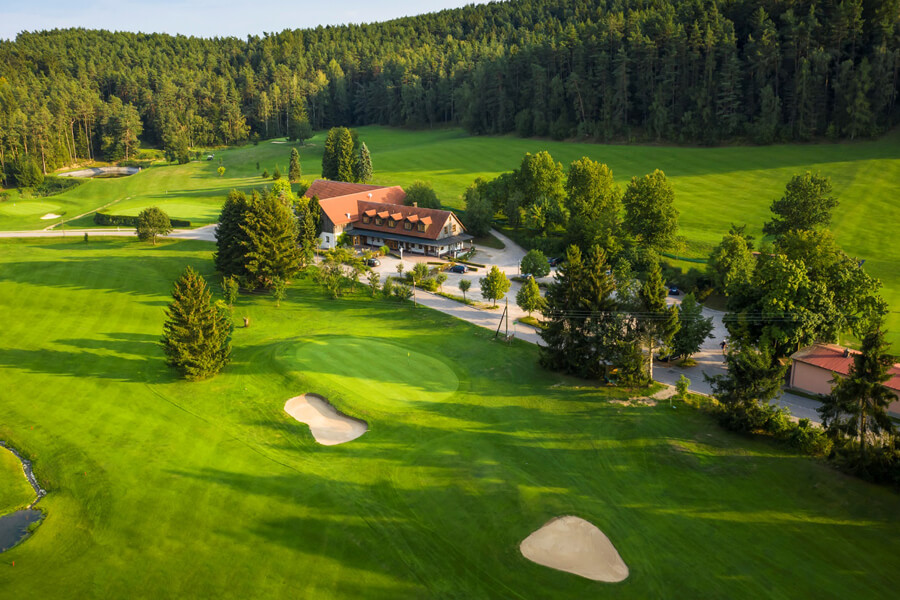 Golfplatz aus Vogelperspektive mit Wald im Hintergrund