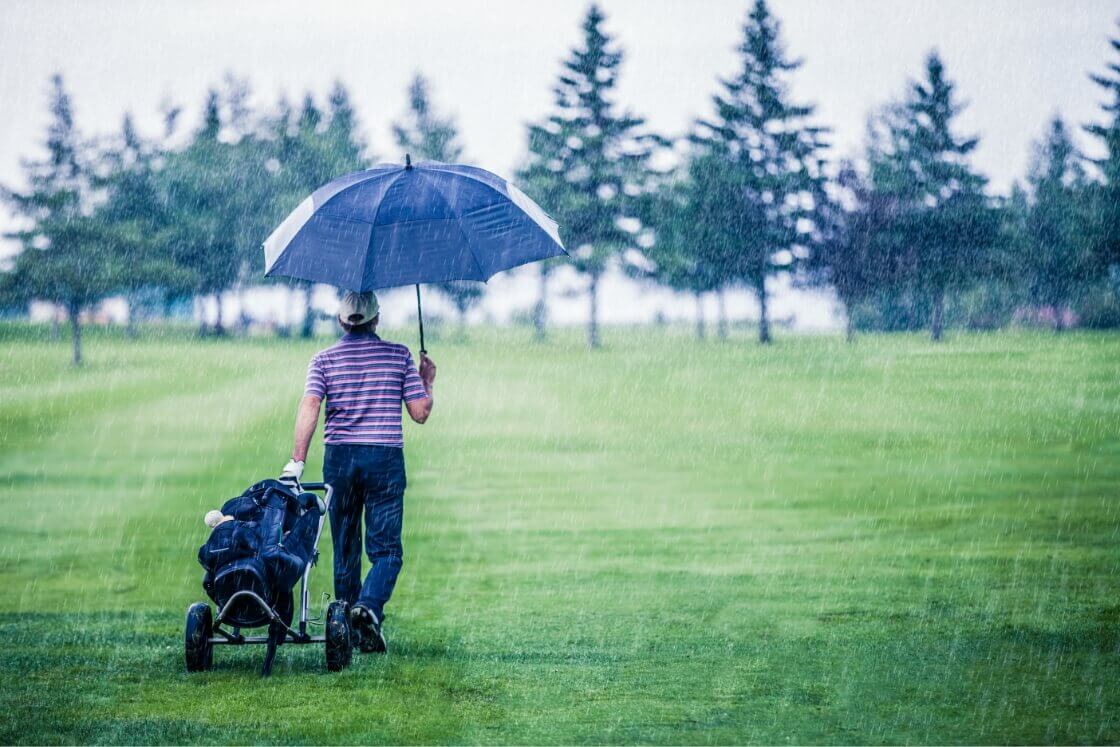 Golfspieler läuft durch Regen