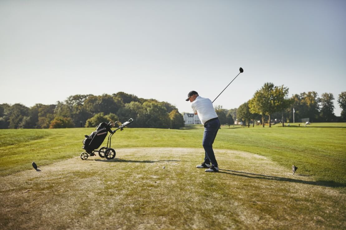 Mann schlägt Golfball mit Driver