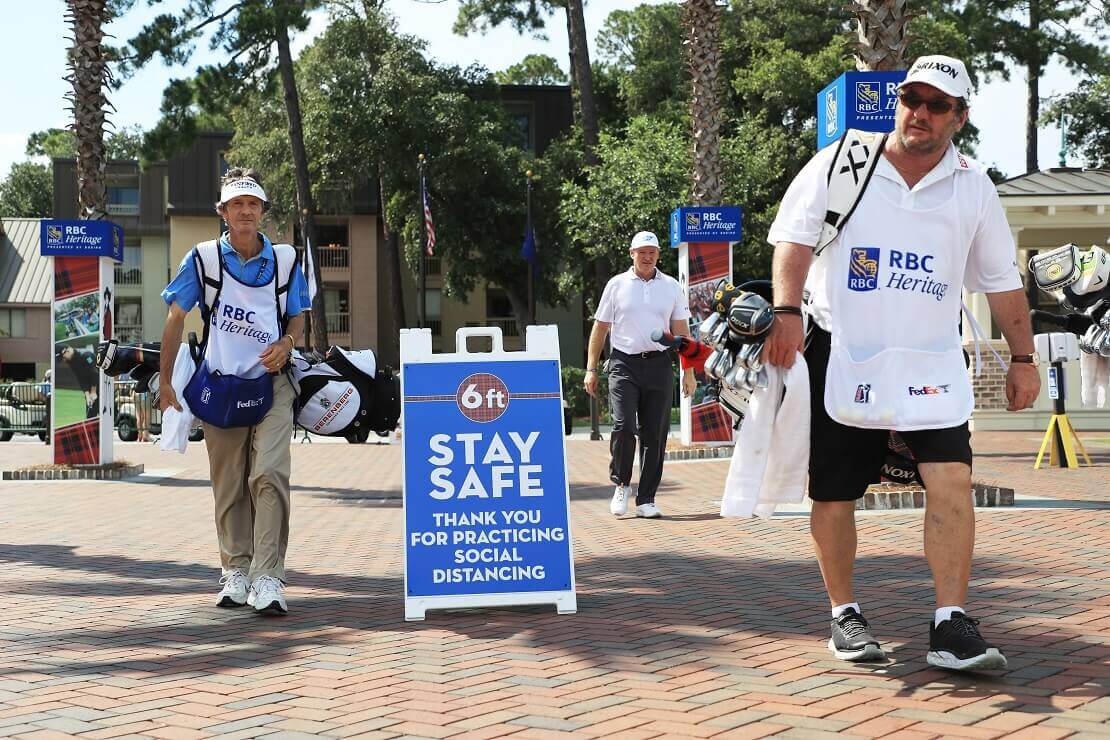 Zwischen den laufenden Caddies steht ein Schild mit der Aufschrift "Stay safe".