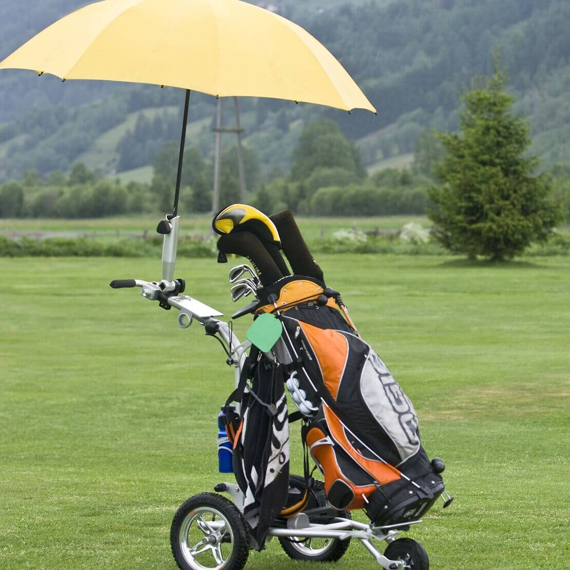 Golfwagen mit angebrachtem Sonneschirm auf dem Grün.