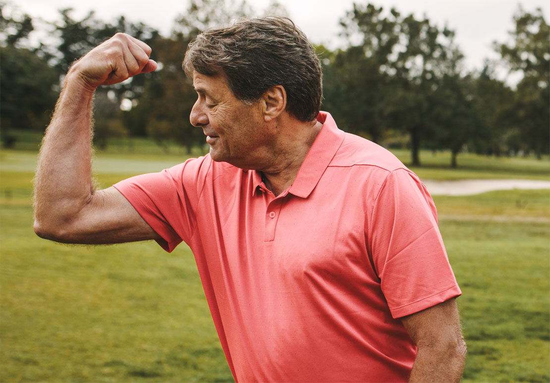 Golfer hält seinen Arm gewinkelt und schaut auf seinen Bizeps.