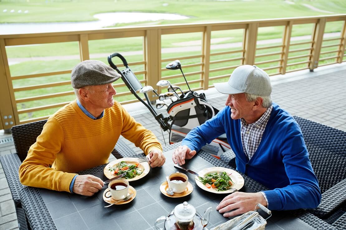 Zwei Senioren essen und trinken Tee im Golfclub