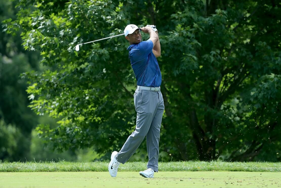 Tiger Woods auf dem Golfplatz mit dem Schläger hinter dem Rücken