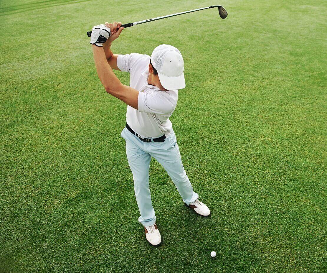 Golfer hält den Schläger beim Rückschwung am höchsten Punkt