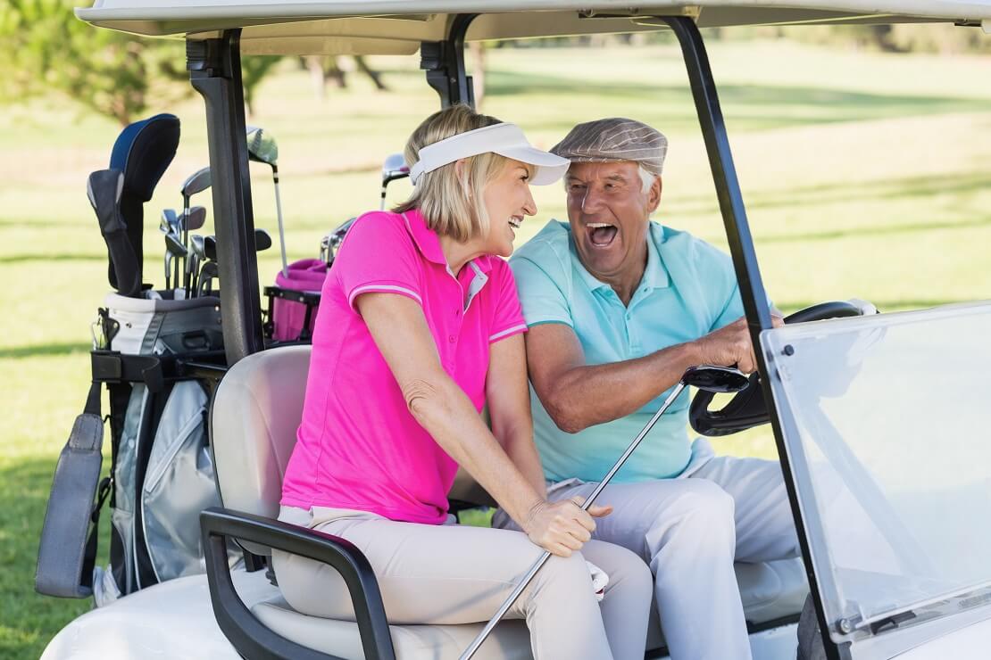 Golfer und Golferin lachen gemeinsam in einem Golf-Cart