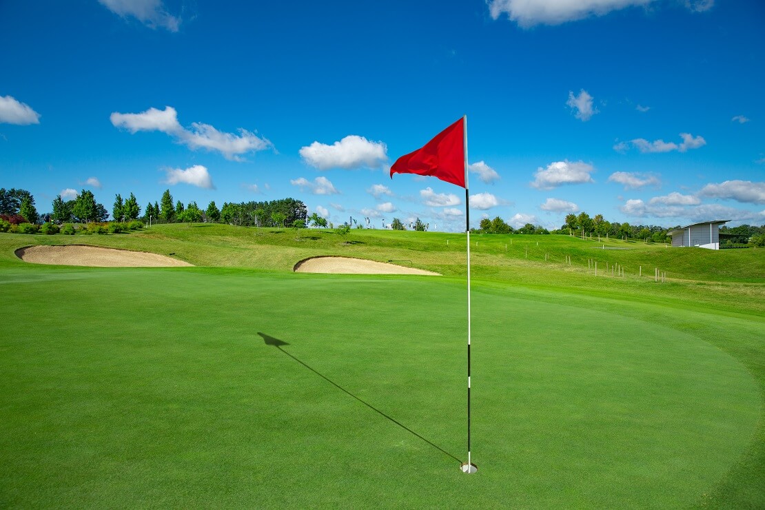 Ein Golfplatz mit einer Fahne im Vordergrund