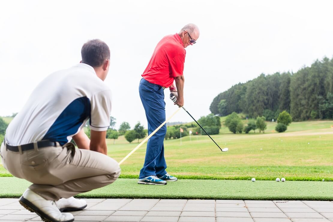 Golfer übt seinen Golfschwung mit einem anderen Golfer