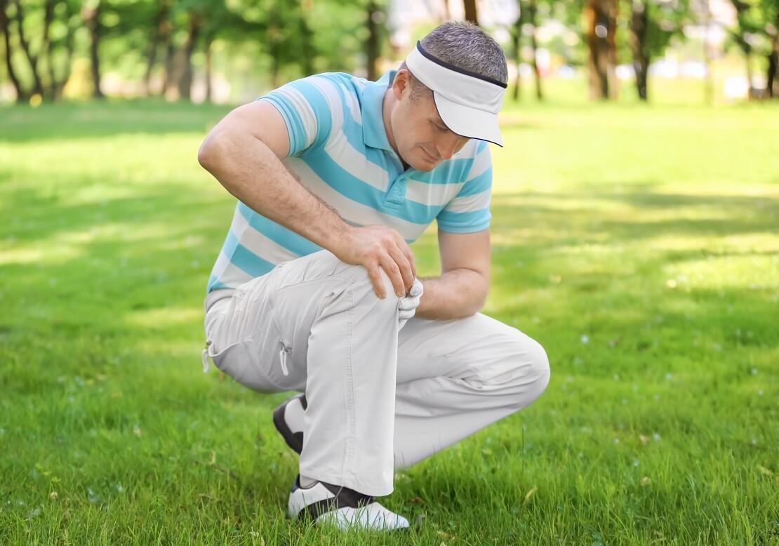 Golfer hält sich schmerzverzerrt das Knie