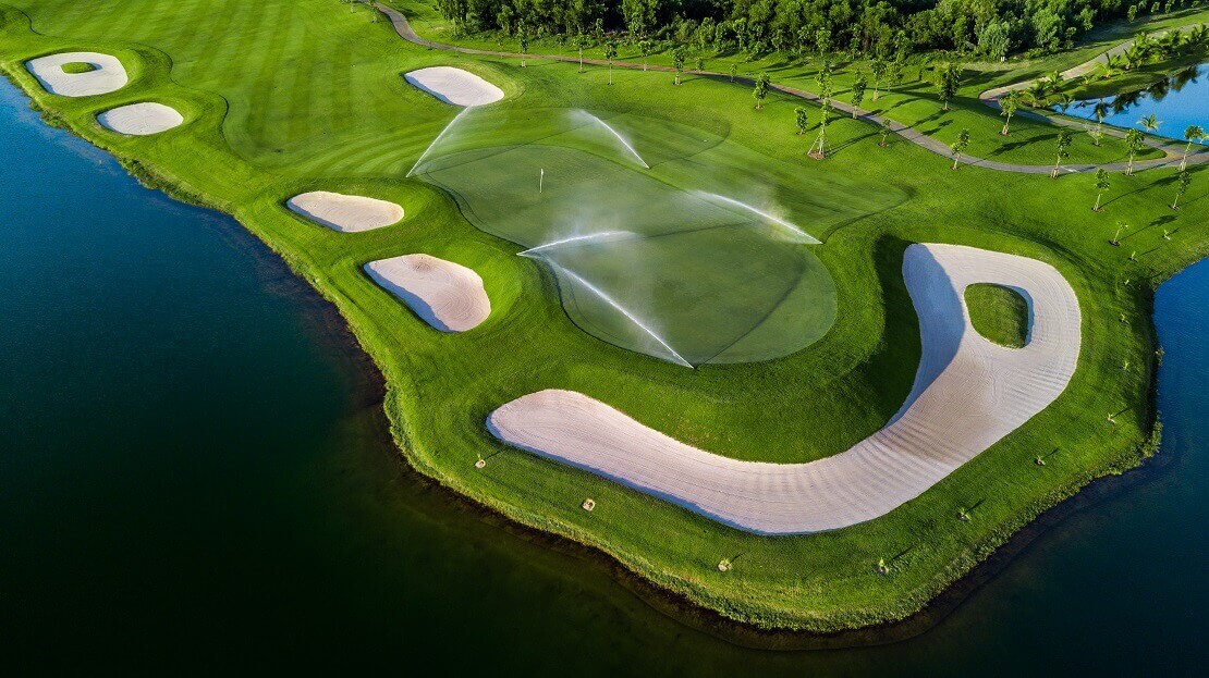 Vogelperspektive eines Golfgrüns mit Sandbunkern und Rasensprengern