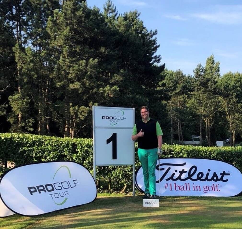 Golfer steht auf dem Grün eines Golfplatzes vor dem Pro Tour Schild