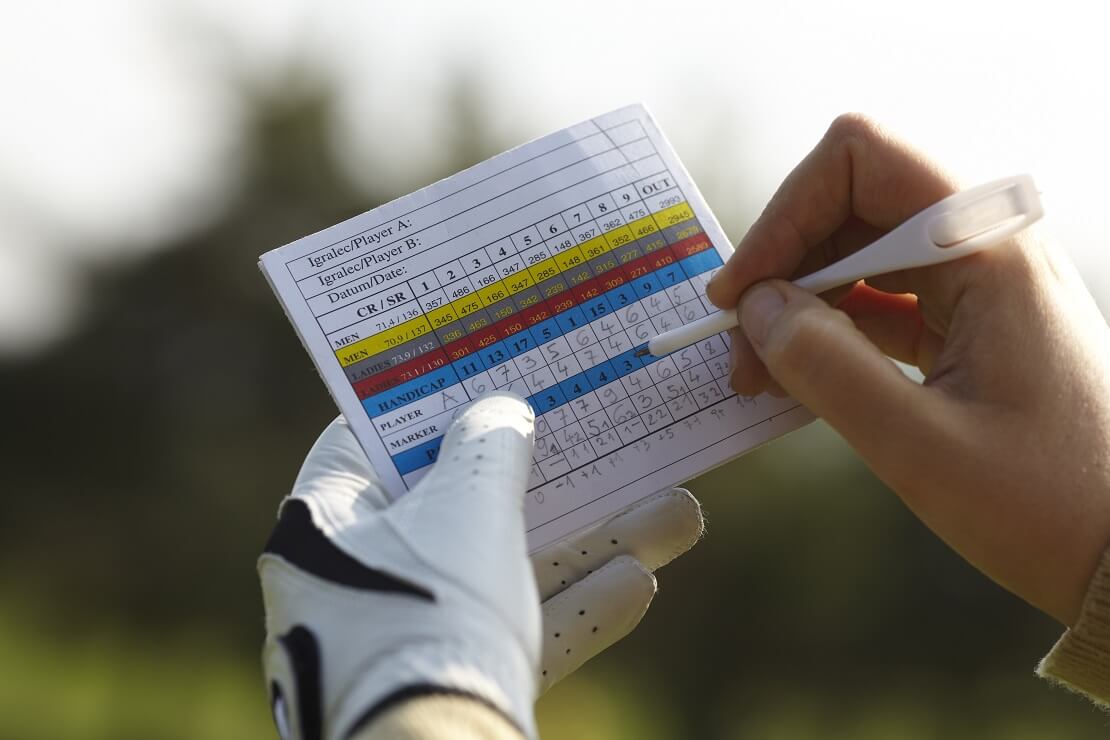 Scorekarte und Stift in den Händen eines Golfers
