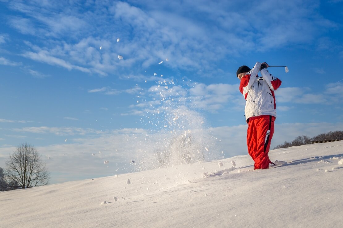 Ein Golfer beim Abschlag im Schnee