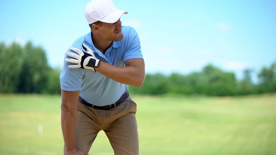 Golfer hält sich schmerzverzerrt die Schulter