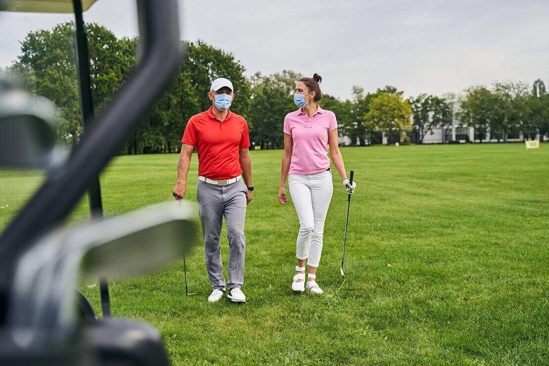 Golfspieler mit Maske auf dem Golfplatz