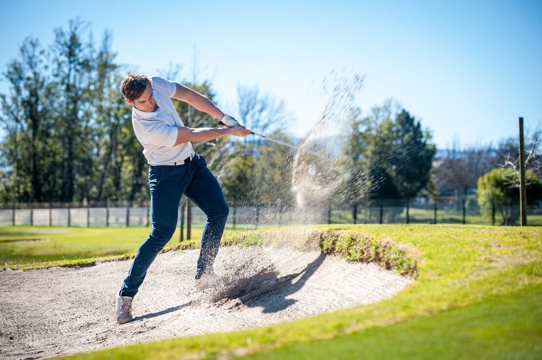 Ein Golfer macht einen Schlag aus einem Bunker