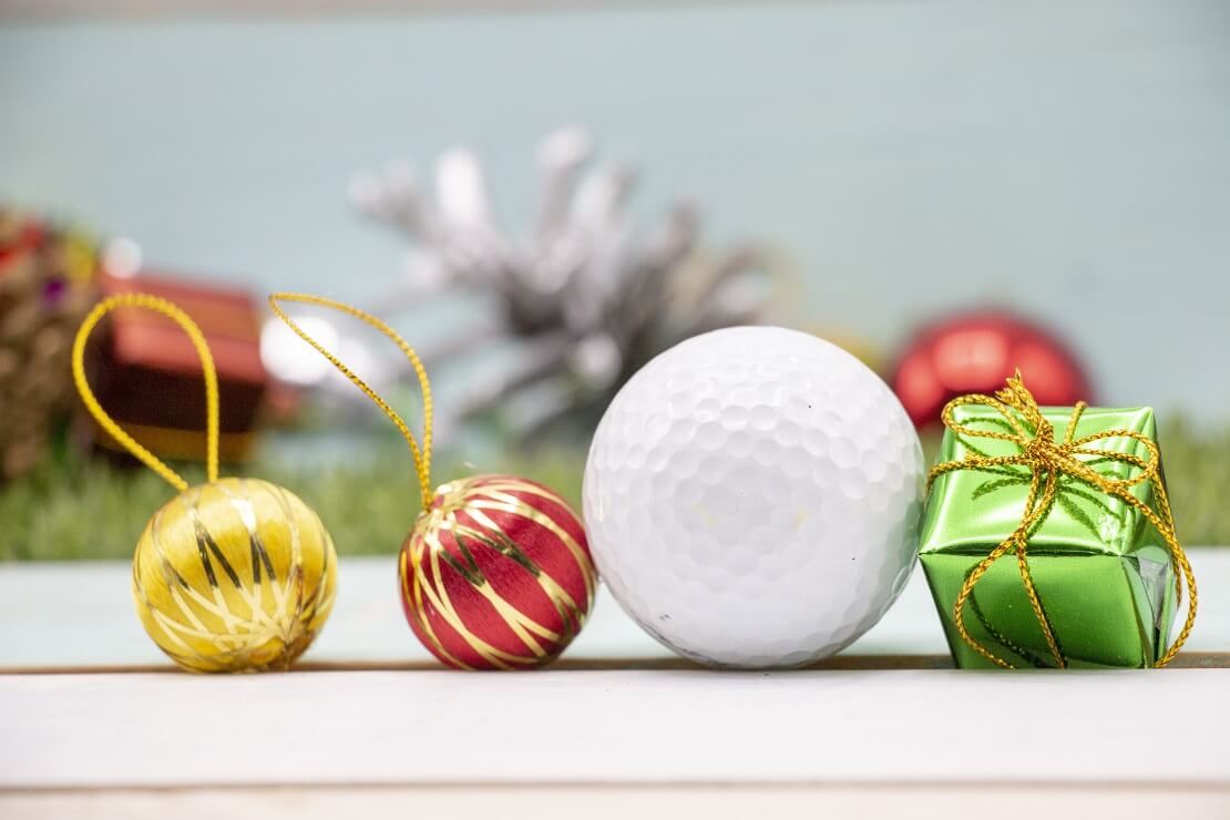 Golfball zwischen Geschenken und Weihnachtskugeln