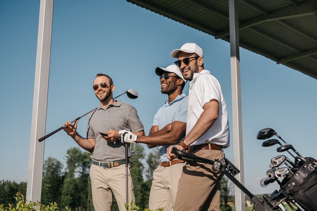 Drei Golfer stehen zusammen und lachen