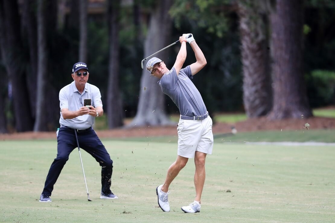 Justin Thomas schlägt seinen Ball und sein Vater Mike fotografiert es im Hintergrund