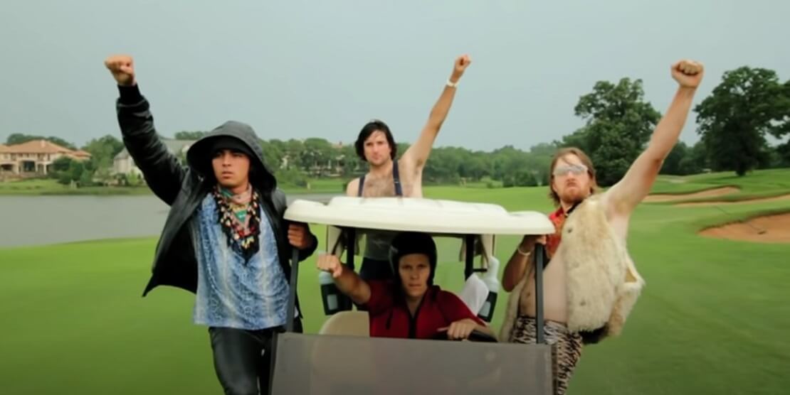 Rickie Fowler, Bubba Watson, Ben Crane und Hunter Mahan sitzen in schrägen Kostümen auf einem Golfcart und reißen jeweils einen Arm in die Luft