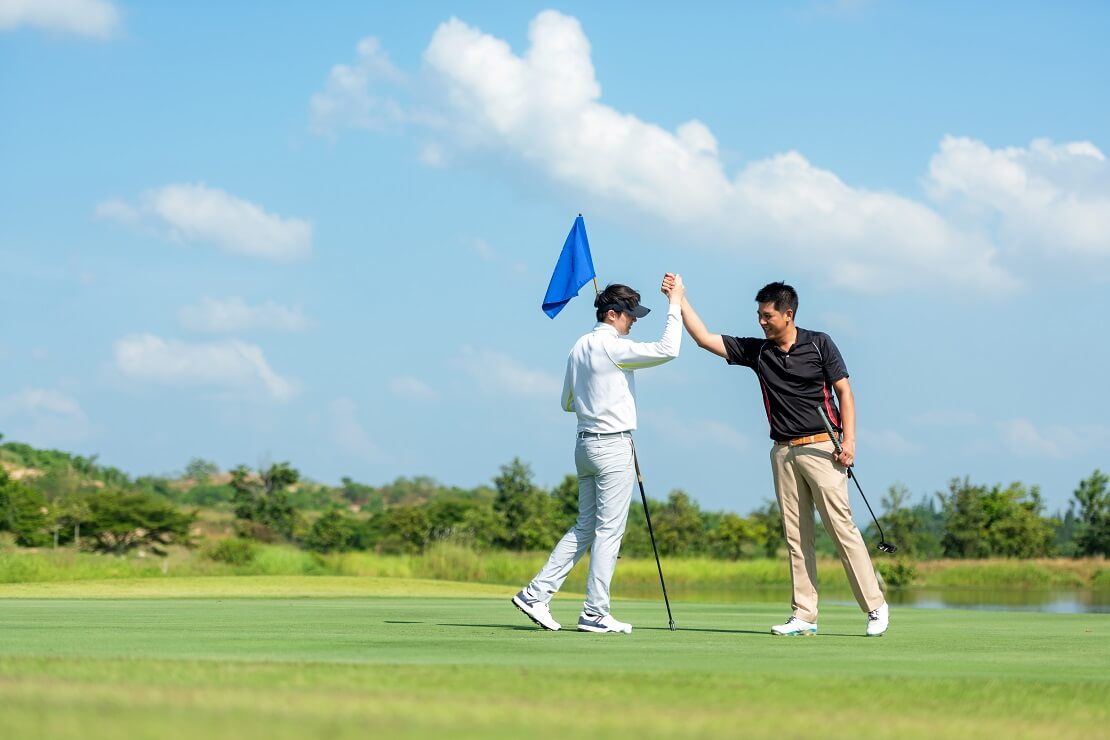 Golfer klatschen nach dem Einlochen gegenseitig ab.