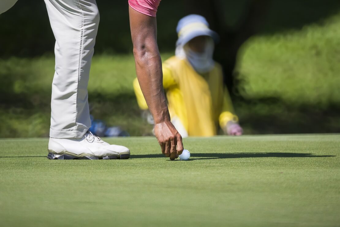 Golfer markiert seinen Ball mit einer Ballmarke