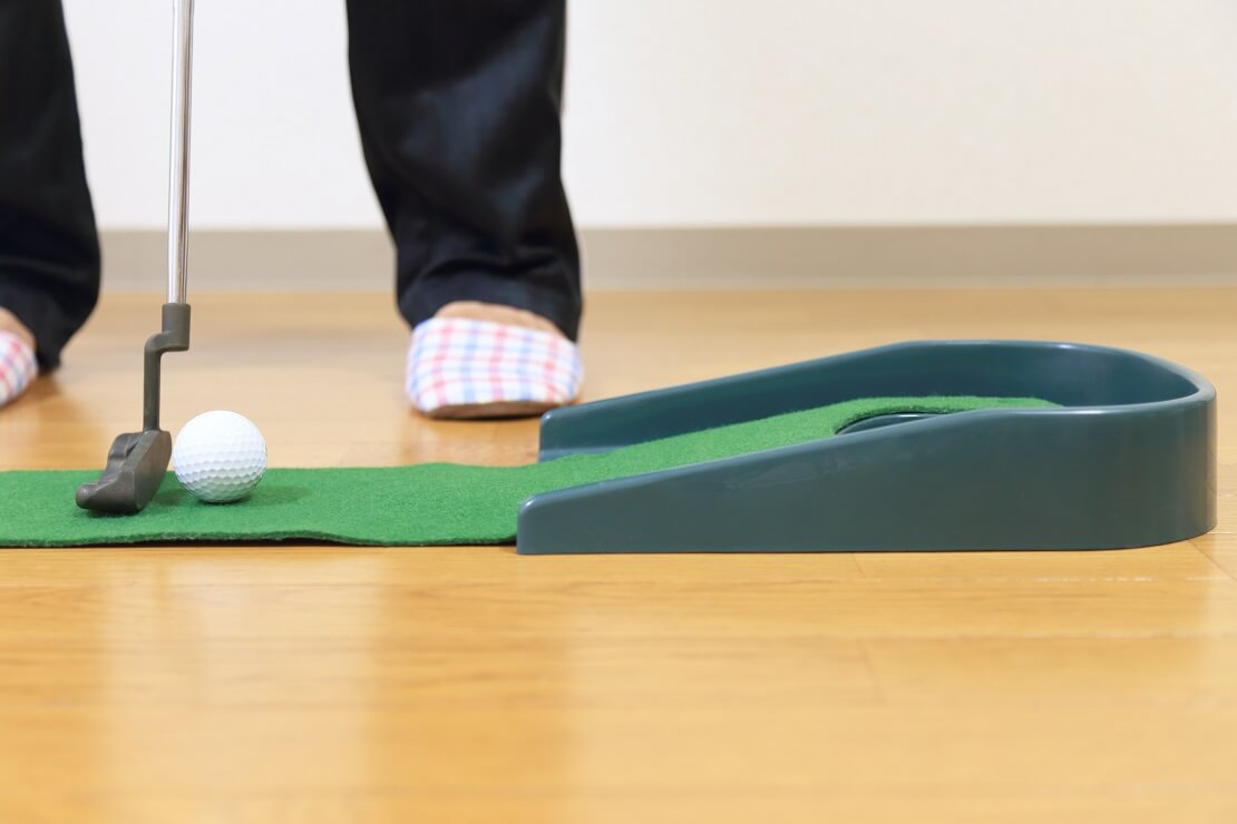 Golfer versucht einen Ball auf einer Putting-Matte einzulochen