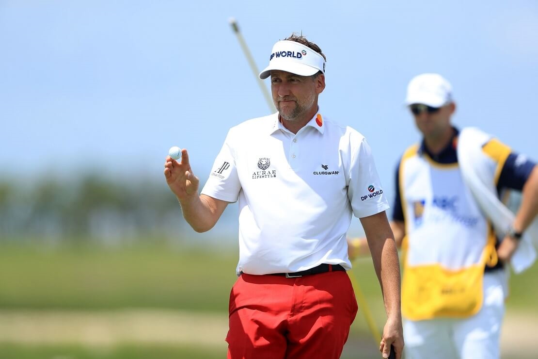 Ian Poulter hält den Ball im Laufen in der Hand, Caddy im Hintergrund