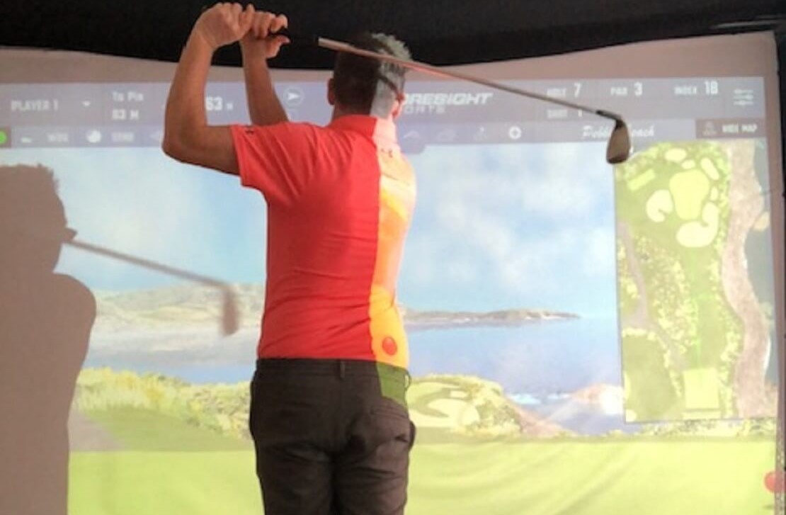 Golfer vor einem Golfsimulator spielt den Pebble Beach Kurs