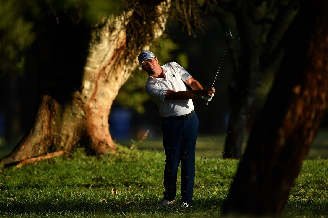 Scott Hend macht einen Golfschlag zwischen Bäumen