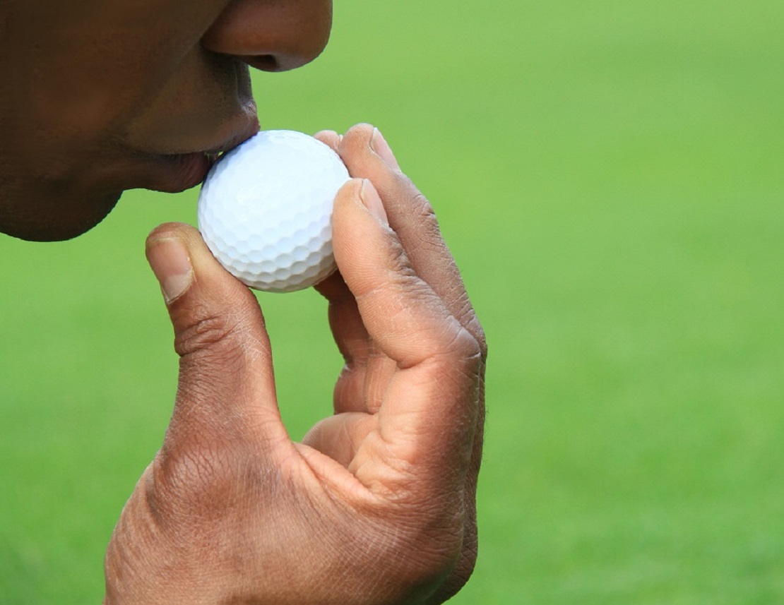 Mann gibt einem Golfball einen Kuss