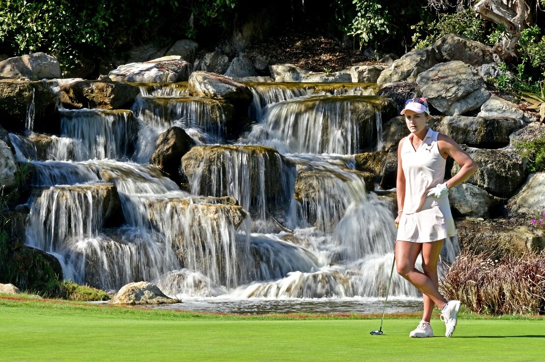 Lexi Thompson steht im Golfdress vor einem Wasserfall