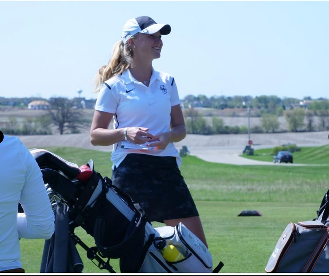 Sophie Hausmann steht lachend hinter ihrer Golftasche