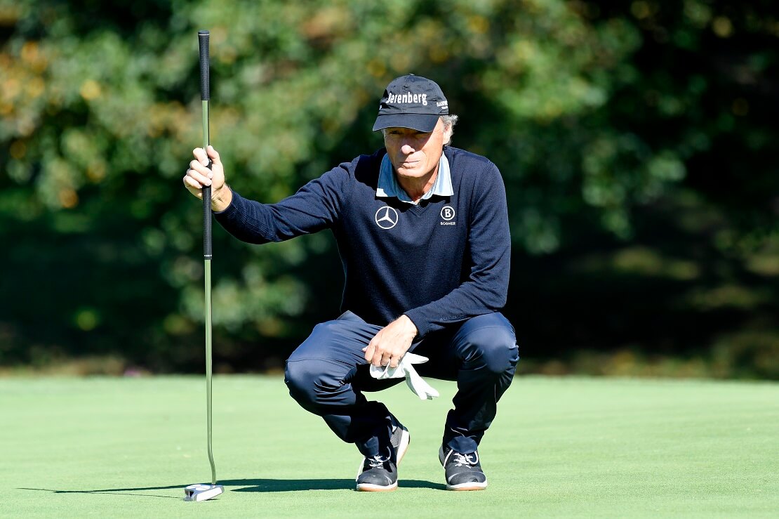 Bernhard Langer hockt mit dem Putter in der Hand