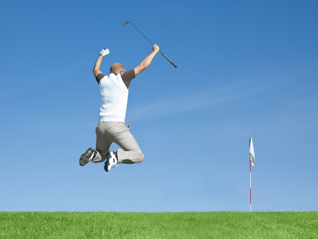 Golfer springt freudig mit seinem Schläger in die Luft.