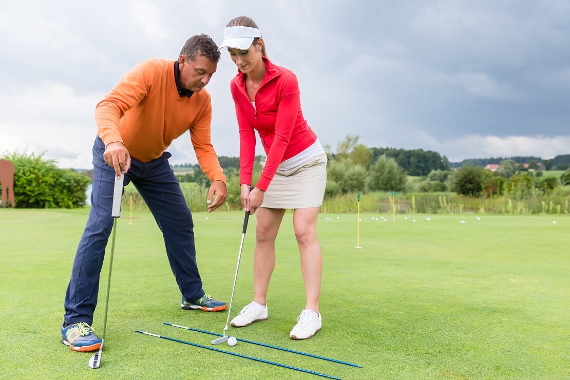 Golfer und Golferin beim Putt-Training