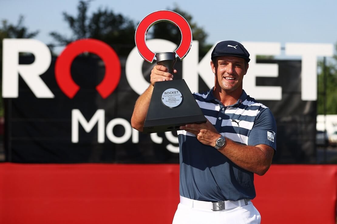 Bryson DeChambeau hält die Trophäe der Rocket Mortgage Classic in den Händen