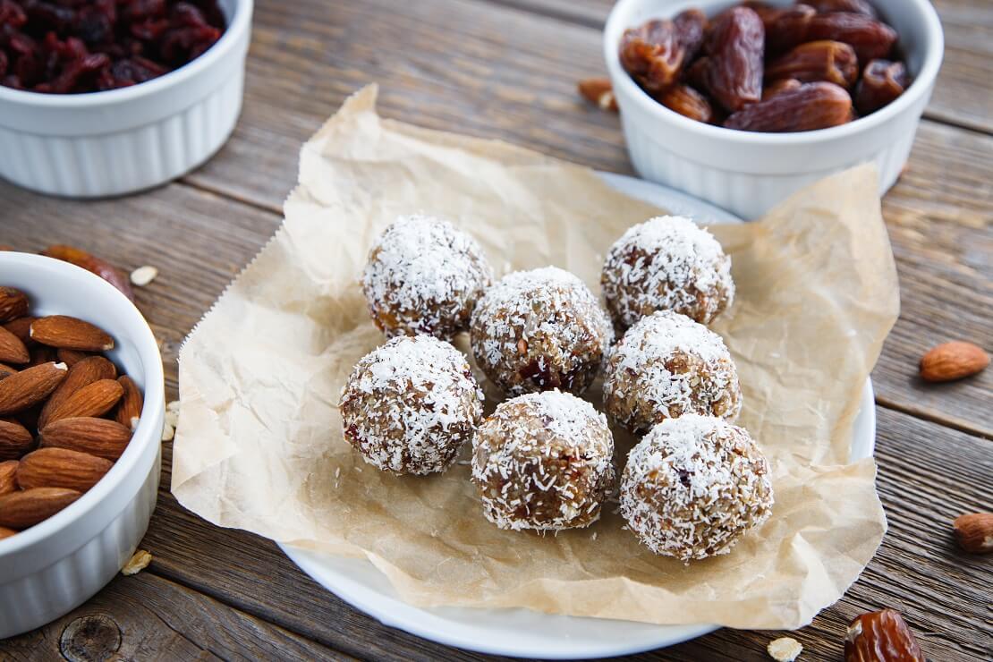 Energyballs auf einem Teller mit Nüssen und Datteln