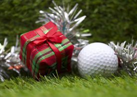 Golfball und Geschenk mit Deko auf Rasen