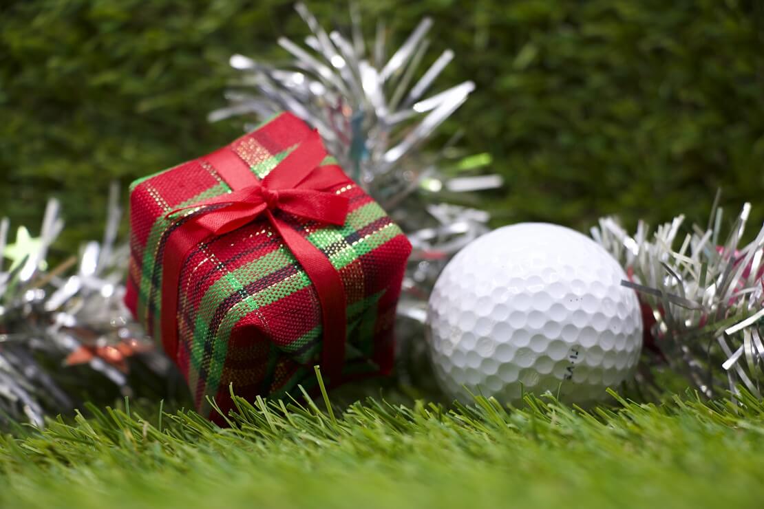 Golfball und Geschenk mit Deko auf Rasen