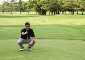 Golfer auf dem Grün hält seinen Putter vor sich