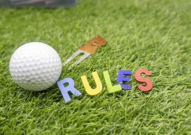 Golfball "Rules" und Pin auf Rasen