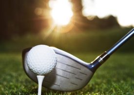 Nahaufnahme von einem Golfball mit Golfschläger dahinter