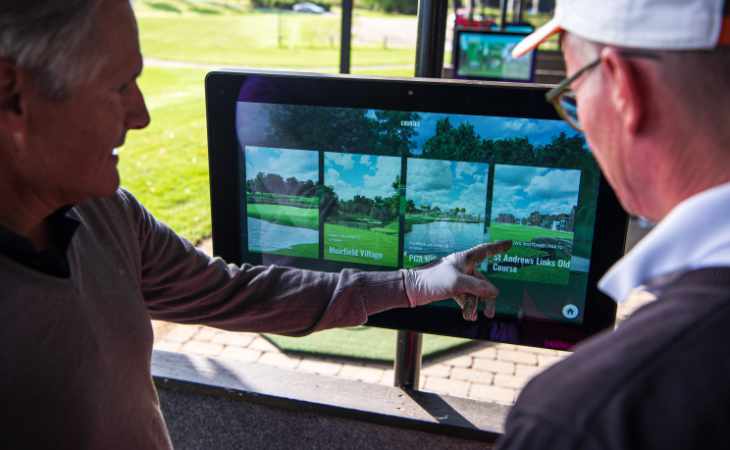Ein Golfer erklärt einem anderen Golfer eine digitale Anzeige
