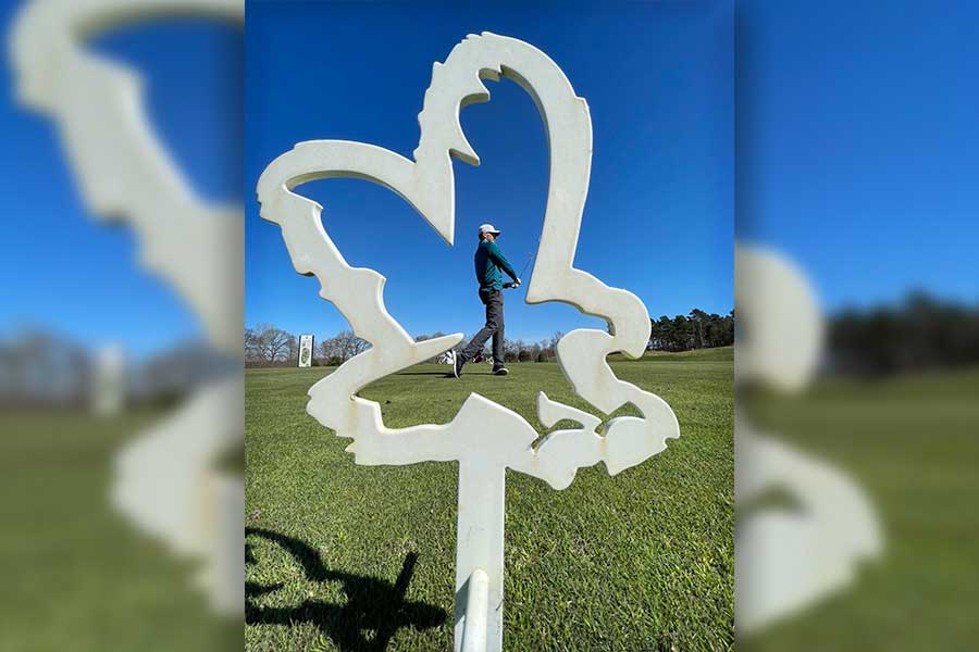 Ein Golfer steht hinter einer Adlerform auf einem Golfplatz