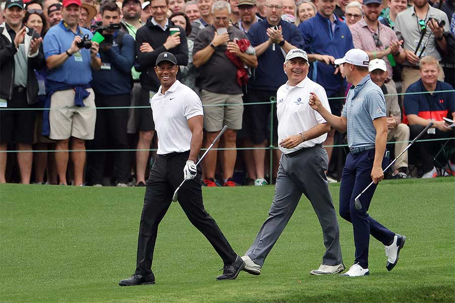 Tiger Woods, Fred Couples und Justin Thomas laufen mit Golfschlägern in der Hand zusammen zum nächsten Tee, im Hintergrund Fans