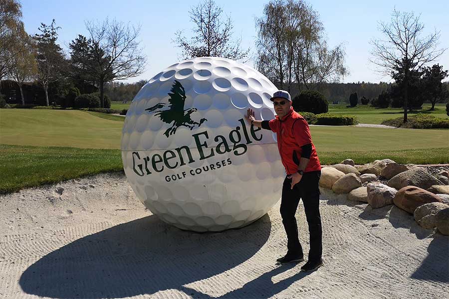 Ein Mann steht neben einem menschengroßen Golfball