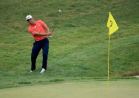 Jon Rahm steht am Rande des Putting Green und chippt