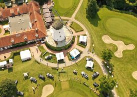 Ein Golfplatz aus der Vogelperspektive, in der Mitte eine Mühle.