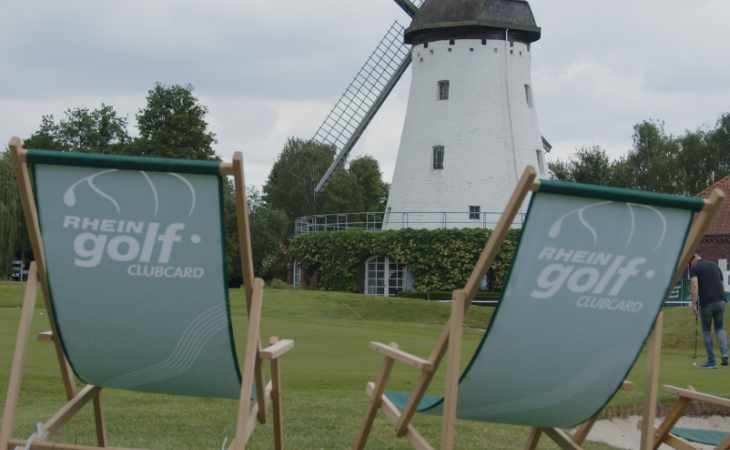 Campingstühle vor einer Windmühle auf einem Golfplatz